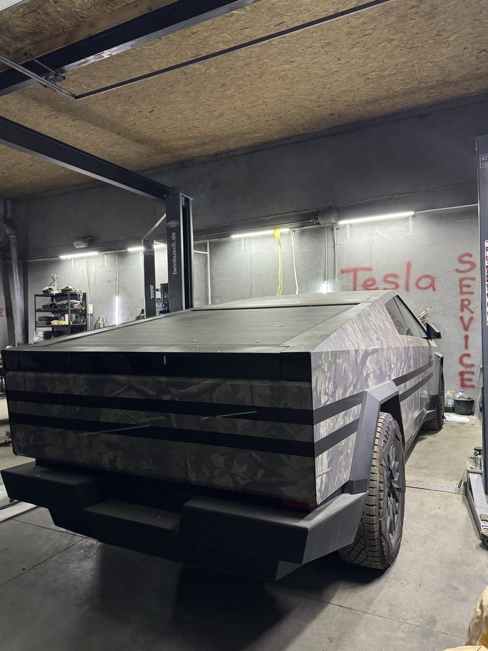 Cybertruck у камуфляжній плівці на підйомнику всередині сервісу