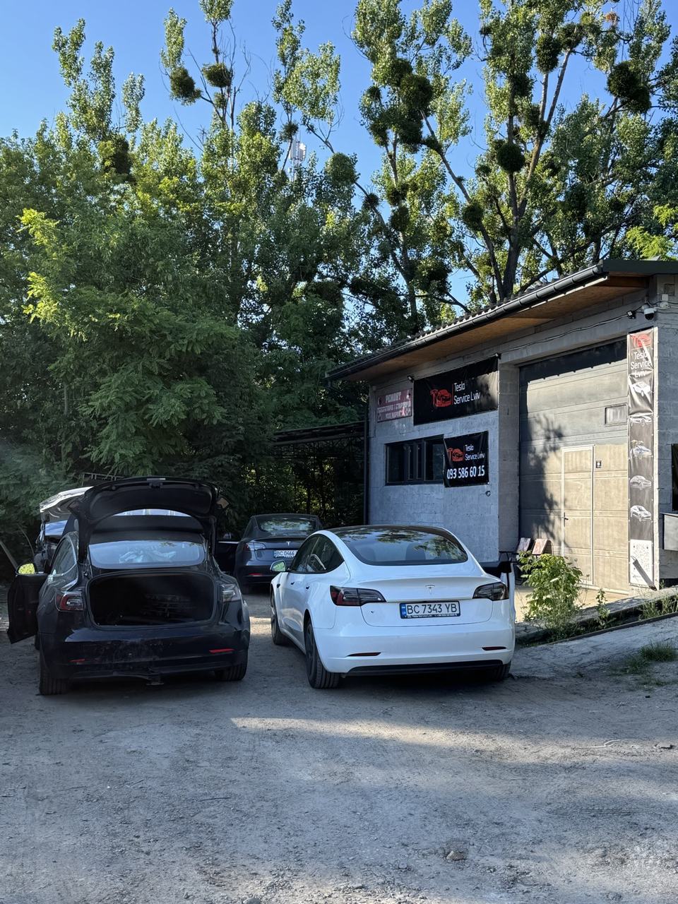 Фасад сервісу з вивіскою Tesla Service Львів і Tesla Model 3 на території